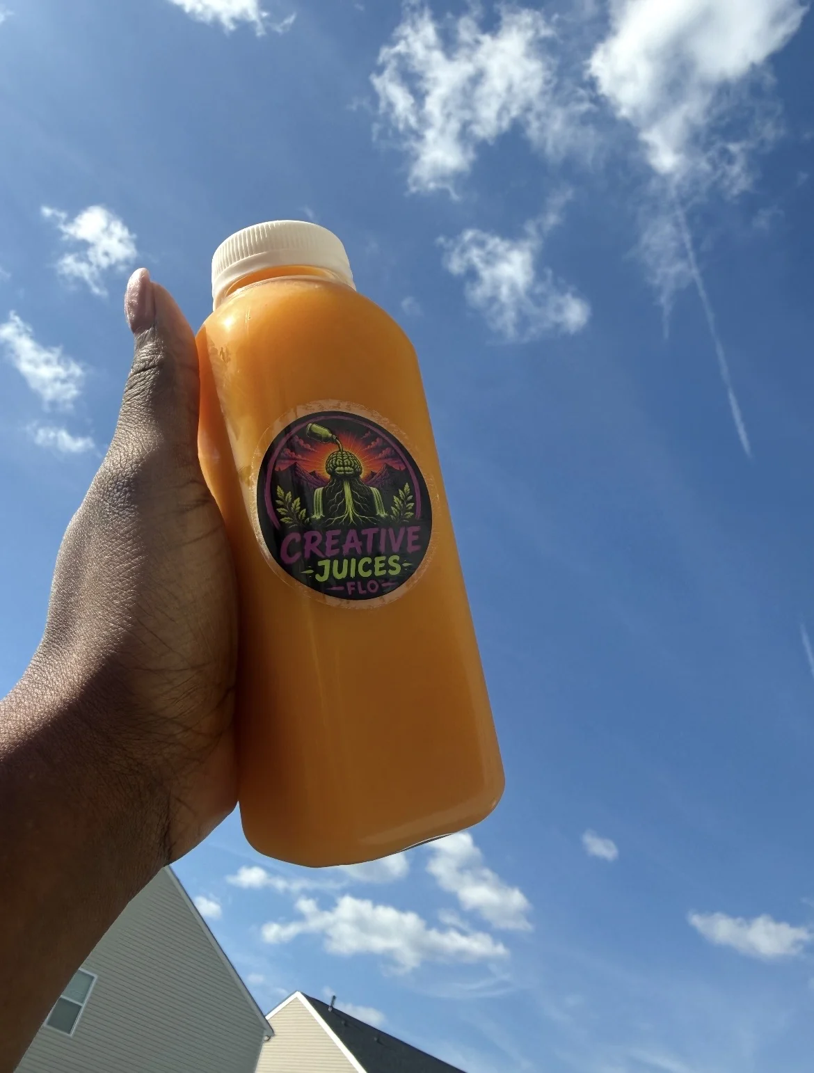 Live orange juice photo held under blue sky